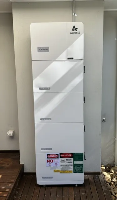 Stacked AlphaESS home battery cabinet installed outdoors with safety labelling