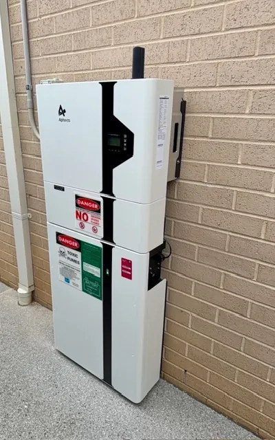 Home battery stack installed in the corner of a cream brick wall