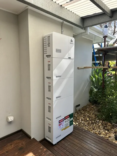 AlphaESS home battery modules mounted on an outdoor ledge beside a deck