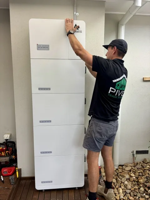 Dan Morgan fitting the top module of a stacked home battery cabinet indoors