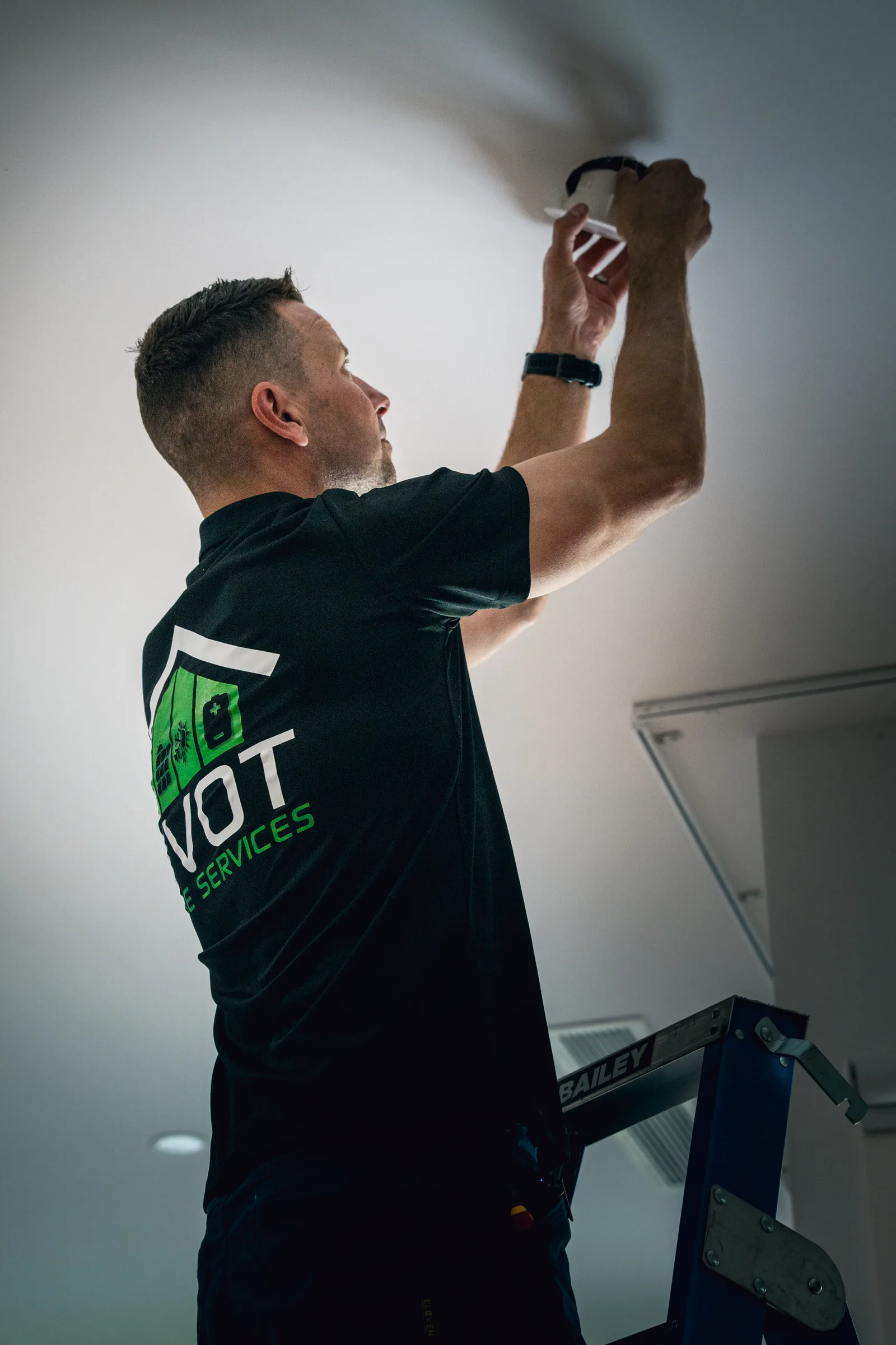 Dan Morgan fitting an LED downlight into a ceiling from a platform ladder
