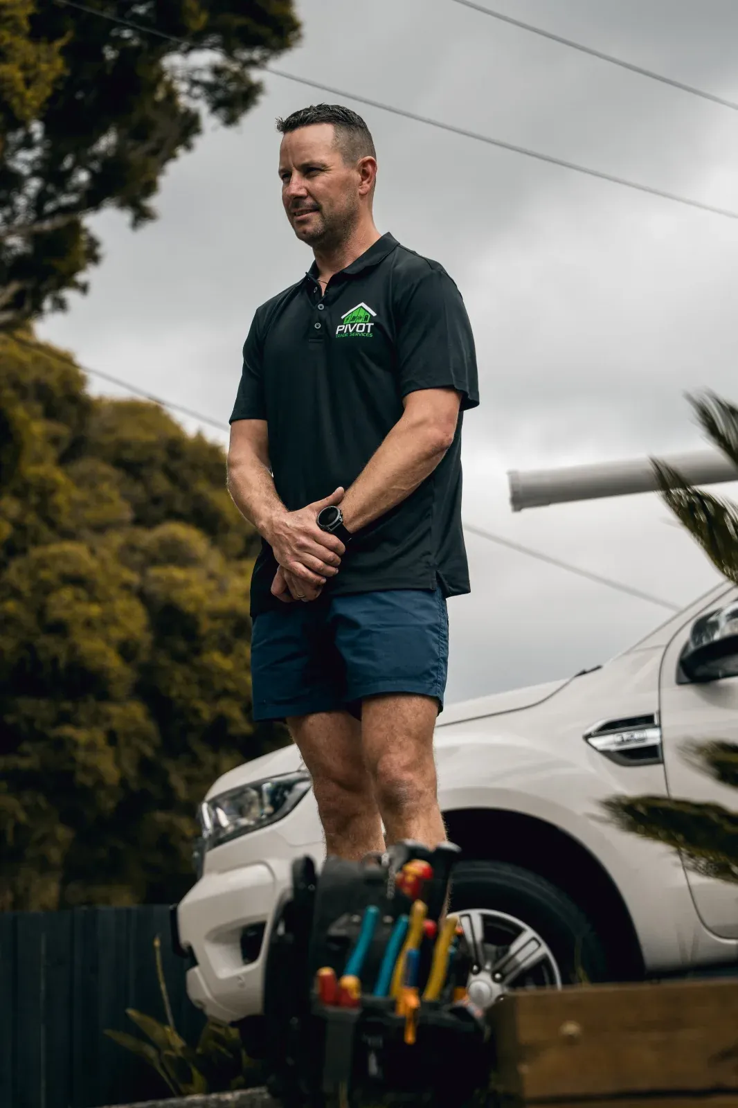 Dan Morgan, lead electrician at Pivot Trade Services, standing beside the work ute with his tool belt
