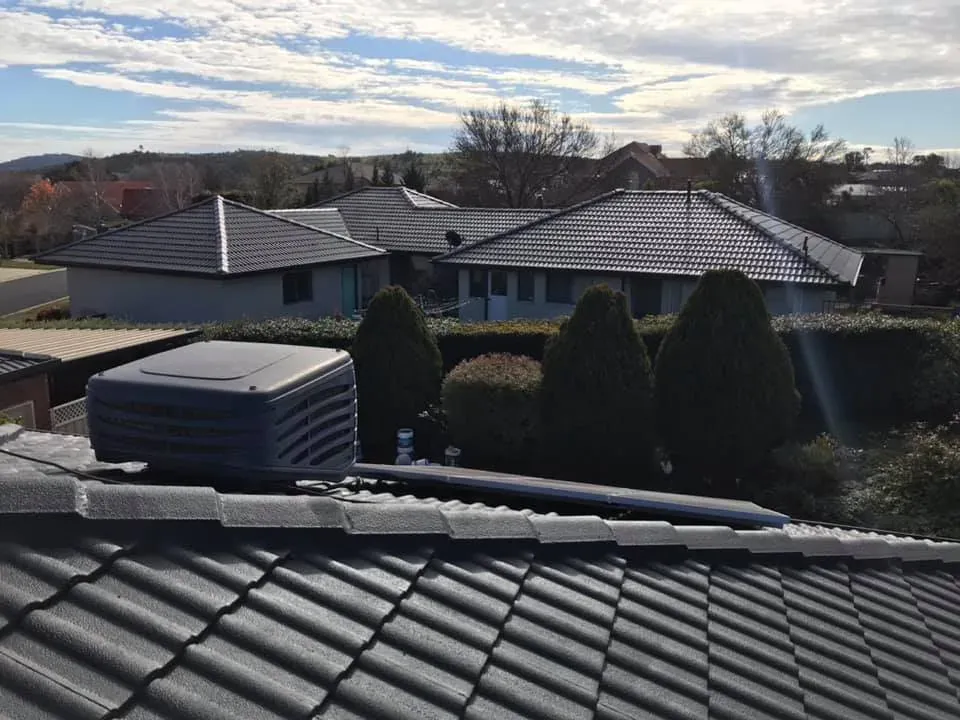Evaporative cooling unit installed on a tiled roof in a Melbourne suburban street