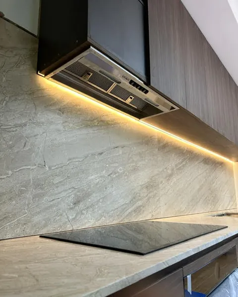 Induction cooktop set into a stone benchtop in a modern kitchen with under-cabinet lighting