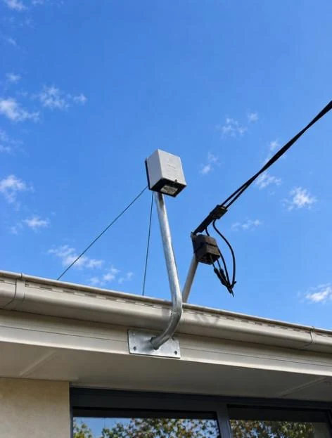 New consumer mains and service bracket installed above the gutter line against a blue sky