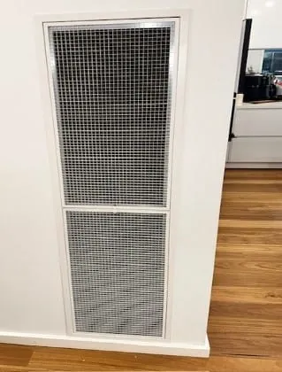 Return air filter grille in a hallway ceiling with the filter partly withdrawn