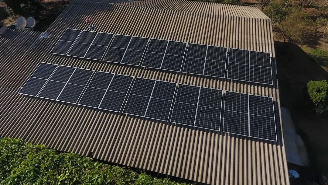 Aerial view of two rows of solar panels installed along a long corrugated roof