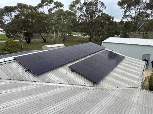 Solar array installed across a colorbond shed roof surrounded by gum trees