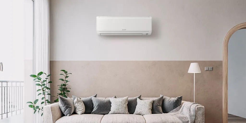 Wall-mounted split system air conditioner above a sofa in a bright living room