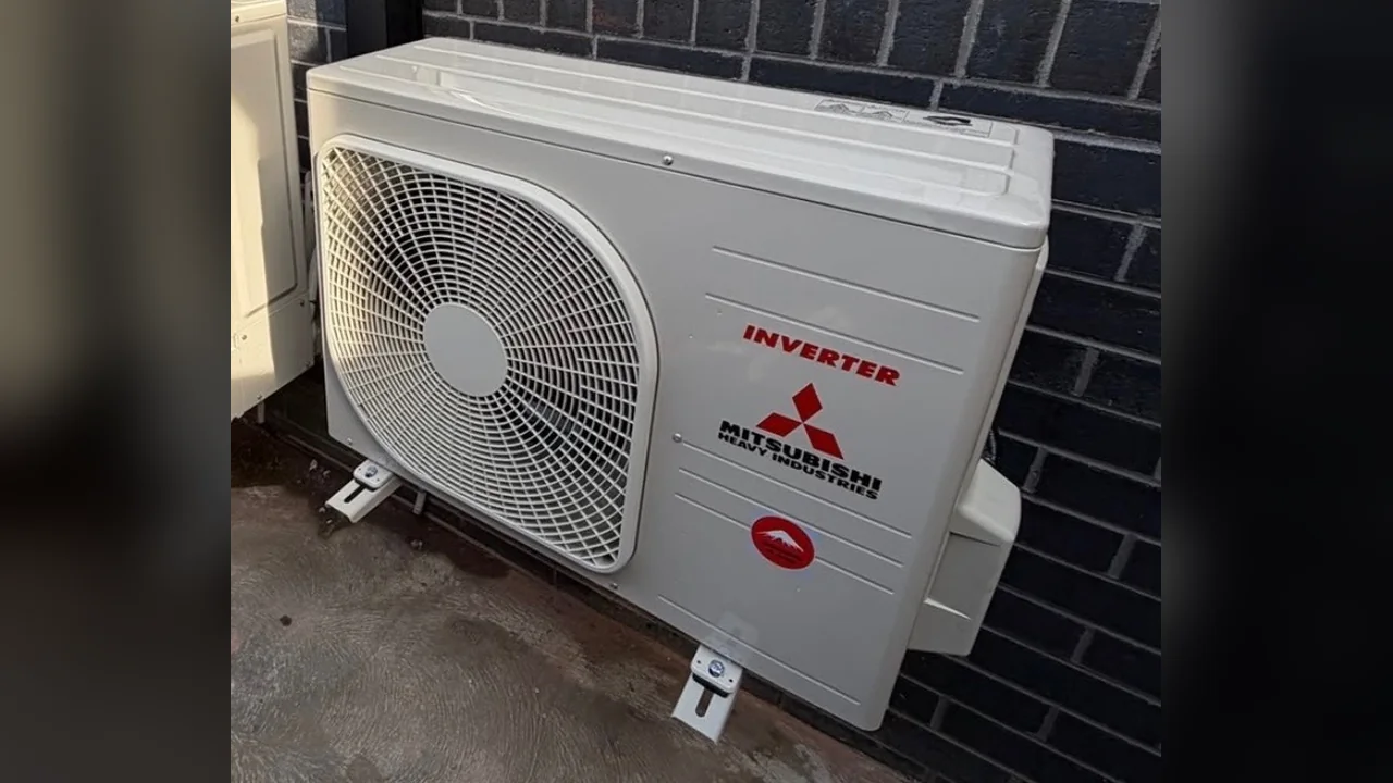 Mitsubishi Heavy Industries inverter split system outdoor unit on feet against a dark brick wall